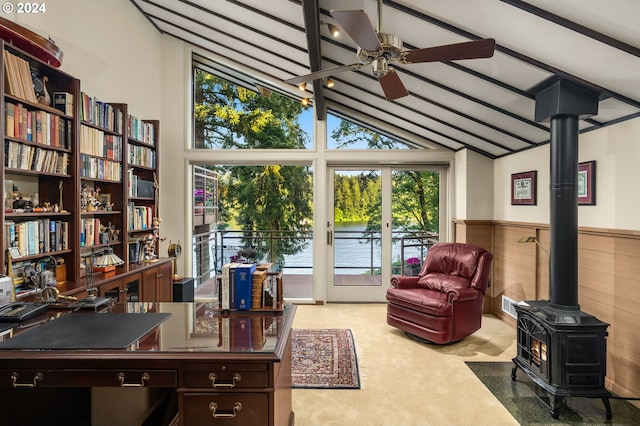 office space featuring a wood stove, beamed ceiling, carpet, and a wealth of natural light