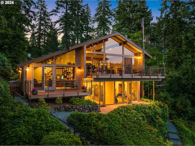 back house at dusk with french doors, a patio area, and a balcony