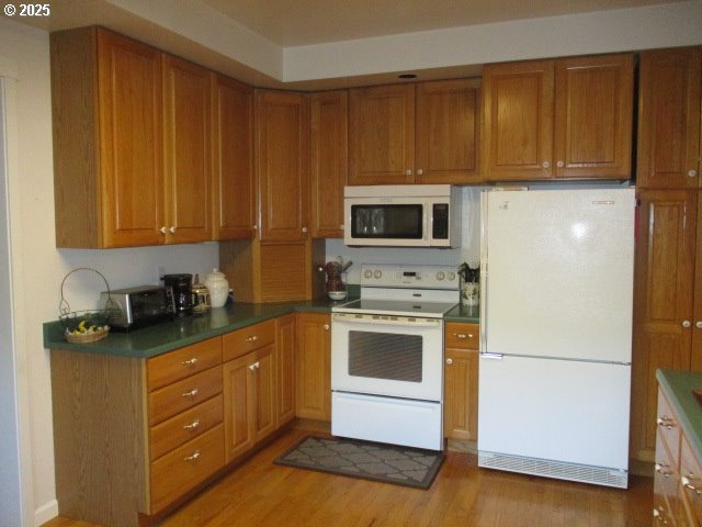 kitchen with white appliances and light hardwood / wood-style floors