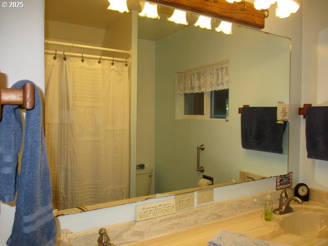 bathroom featuring a shower with curtain, toilet, and sink