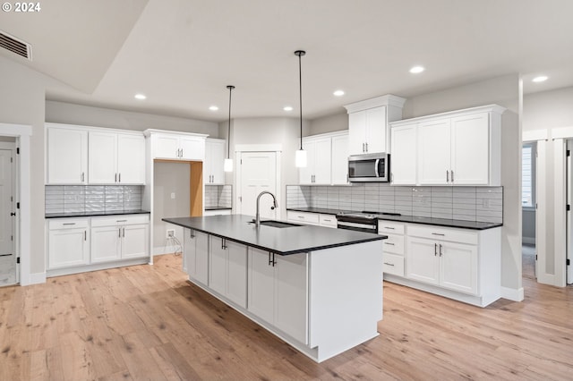 kitchen featuring stainless steel appliances, sink, pendant lighting, white cabinets, and light hardwood / wood-style floors