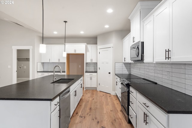 kitchen with white cabinets, appliances with stainless steel finishes, light hardwood / wood-style flooring, and pendant lighting