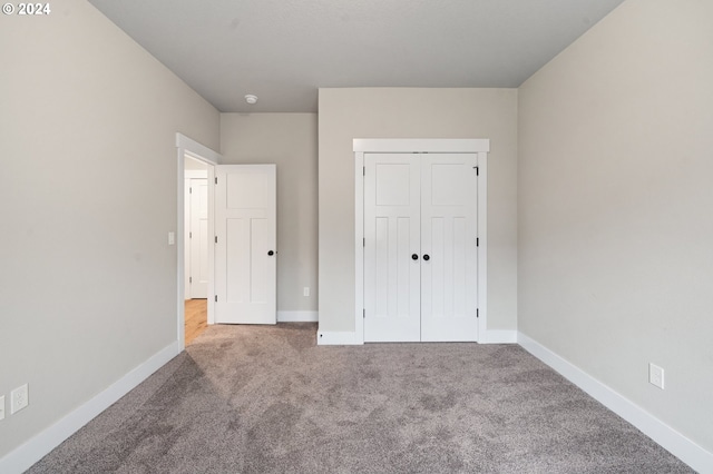 unfurnished bedroom featuring light carpet and a closet