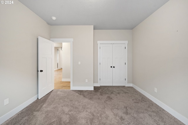 unfurnished bedroom with light carpet and a closet