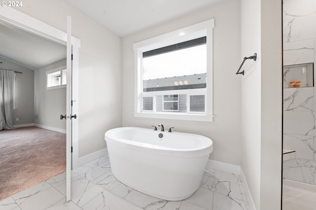 bathroom featuring a tub, a healthy amount of sunlight, and lofted ceiling