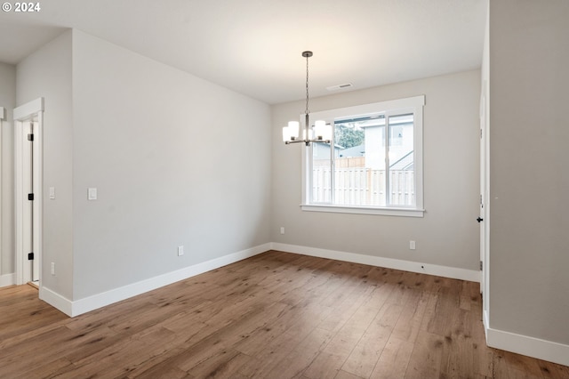 unfurnished dining area with hardwood / wood-style floors and a notable chandelier