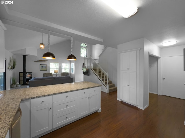 kitchen featuring a wood stove, light stone counters, dark hardwood / wood-style flooring, a textured ceiling, and white cabinets