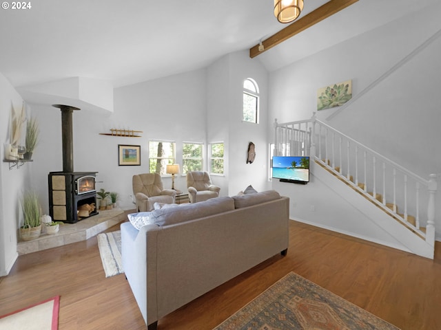 living room featuring beamed ceiling, wood-type flooring, high vaulted ceiling, and a wood stove