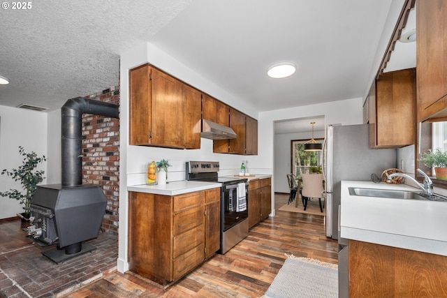 kitchen featuring under cabinet range hood, a sink, appliances with stainless steel finishes, brown cabinetry, and light countertops