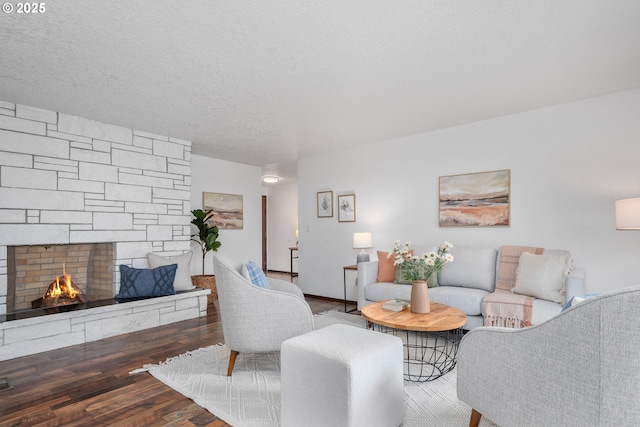 living area featuring a textured ceiling, wood finished floors, and a fireplace