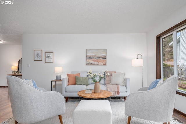 living room with wood finished floors, a healthy amount of sunlight, arched walkways, and a textured ceiling