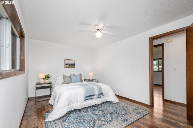 bedroom with a ceiling fan, wood finished floors, baseboards, and a textured ceiling