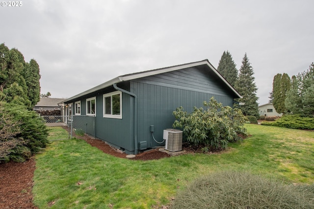 view of side of home featuring a lawn, cooling unit, and fence