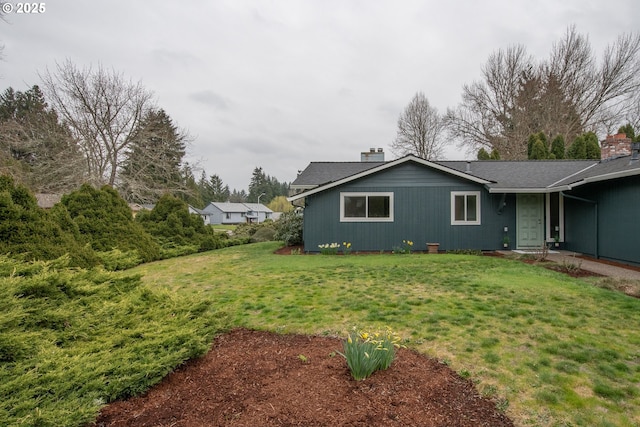 view of side of home with a yard and a chimney