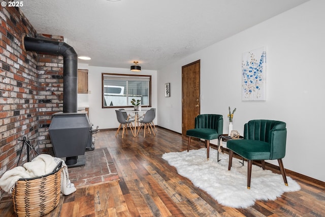 sitting room featuring hardwood / wood-style flooring, a wood stove, baseboards, and a textured ceiling