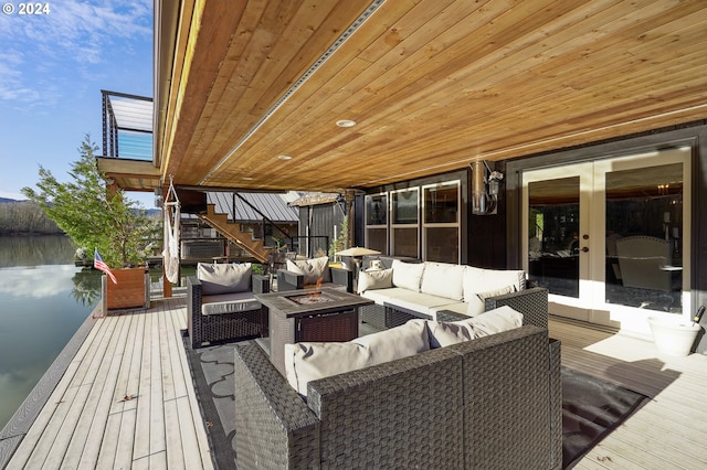 deck featuring french doors, a water view, and an outdoor living space with a fire pit