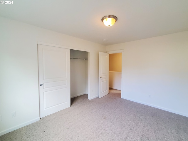 unfurnished bedroom featuring a closet and light colored carpet