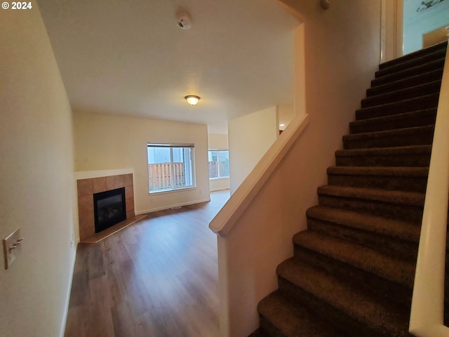 staircase featuring a fireplace and wood-type flooring