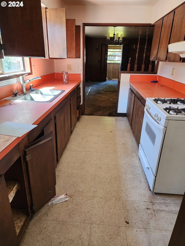 kitchen with white gas stove, light tile floors, and sink