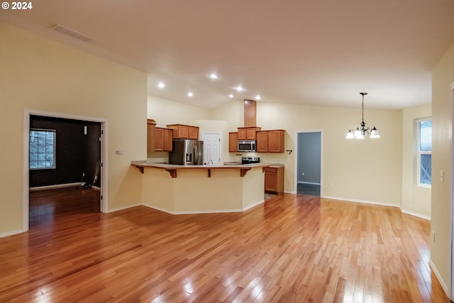 kitchen with stainless steel appliances, an inviting chandelier, light hardwood / wood-style floors, pendant lighting, and a breakfast bar area