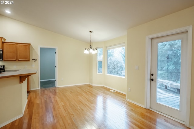 kitchen featuring light wood-type flooring, vaulted ceiling, hanging light fixtures, and a notable chandelier