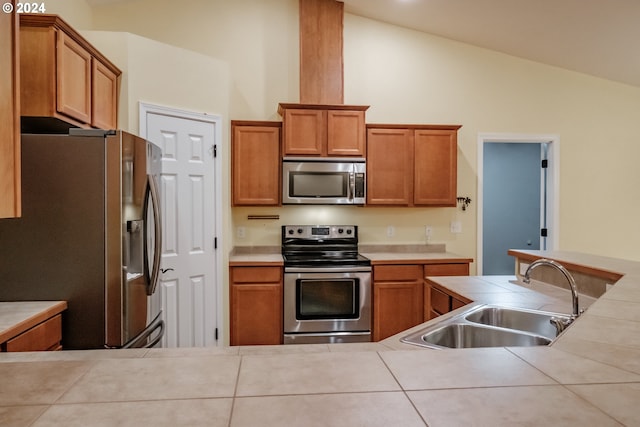 kitchen featuring tile counters, stainless steel appliances, lofted ceiling, and sink