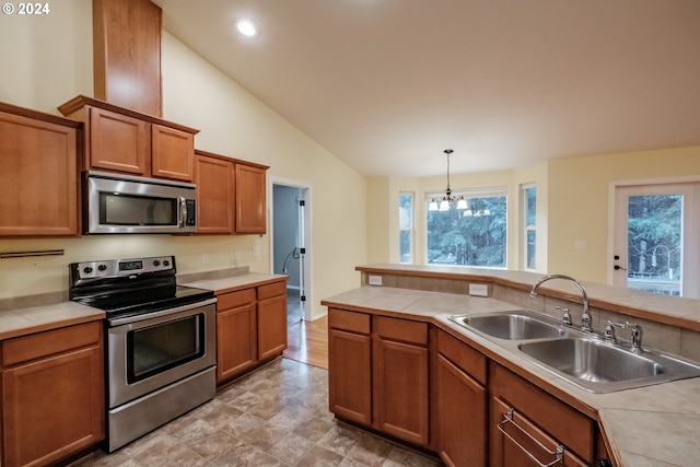 kitchen with an inviting chandelier, sink, decorative light fixtures, tile counters, and stainless steel appliances