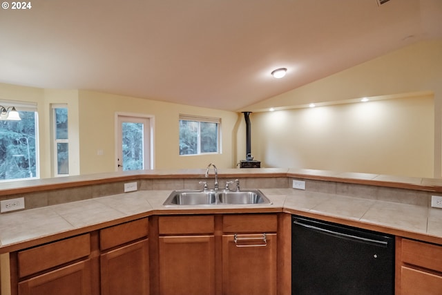 kitchen featuring tile countertops, sink, black dishwasher, and vaulted ceiling