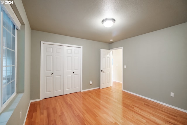 unfurnished bedroom featuring a closet, hardwood / wood-style floors, and a textured ceiling