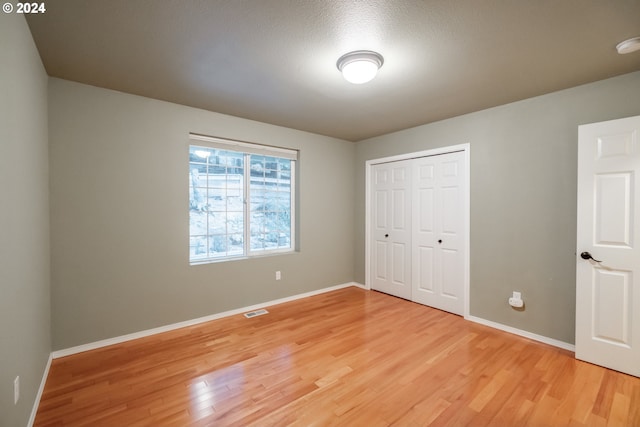 unfurnished bedroom with hardwood / wood-style flooring, a textured ceiling, and a closet