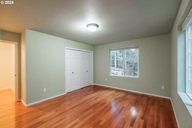 unfurnished bedroom featuring a closet, hardwood / wood-style floors, and a textured ceiling