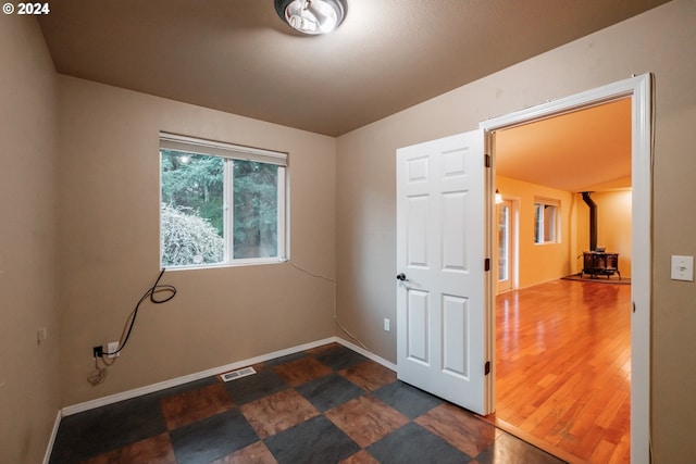 spare room featuring a wood stove and dark wood-type flooring