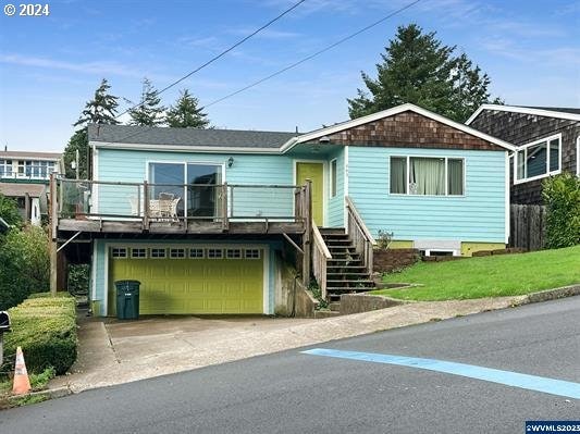 view of front of property with a wooden deck, a garage, and a front lawn