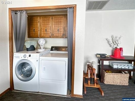 clothes washing area with cabinets and independent washer and dryer