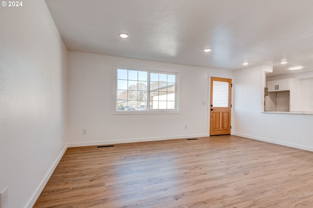 unfurnished room featuring a textured ceiling and light hardwood / wood-style floors