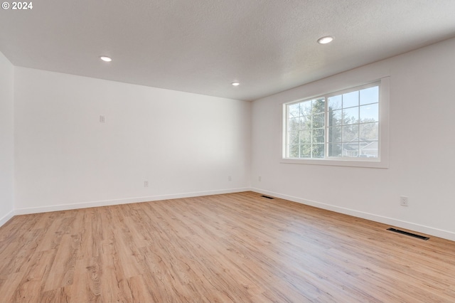 spare room with light hardwood / wood-style floors and a textured ceiling