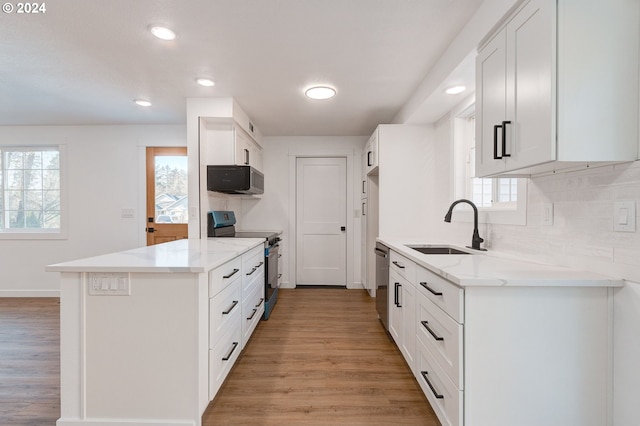 kitchen featuring white cabinets, appliances with stainless steel finishes, light hardwood / wood-style floors, and sink