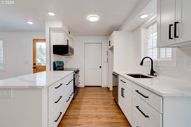 kitchen with appliances with stainless steel finishes, light hardwood / wood-style floors, white cabinetry, and light stone counters