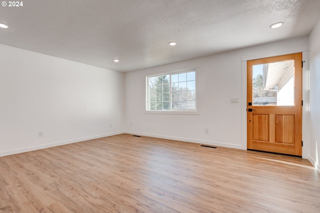 entryway featuring a healthy amount of sunlight, light wood-type flooring, and a textured ceiling