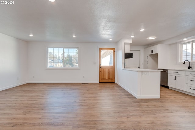 kitchen featuring white cabinetry, dishwasher, a healthy amount of sunlight, and light hardwood / wood-style floors