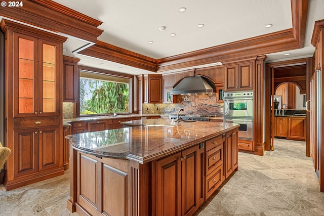 27050 SW Petes Mountain Rd, West Linn, OR 97068 - kitchen featuring ornamental molding, an island with sink, tasteful backsplash, brown cabinets, and dark stone countertops
