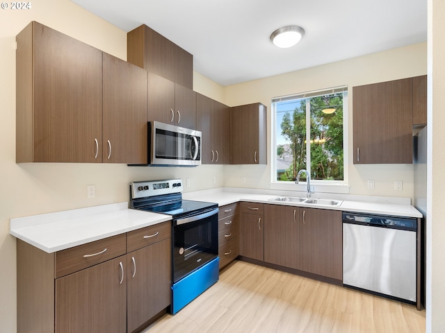 kitchen with sink, light wood-type flooring, stainless steel appliances, and dark brown cabinetry