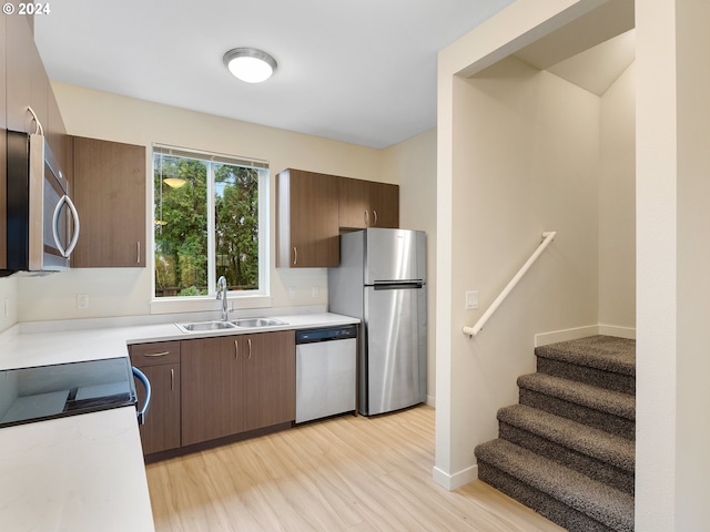 kitchen with dark brown cabinetry, sink, light hardwood / wood-style floors, and appliances with stainless steel finishes