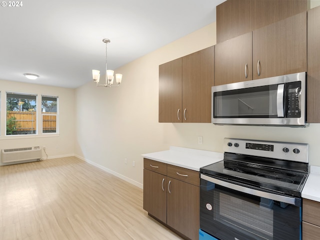 kitchen featuring stainless steel appliances, light hardwood / wood-style flooring, an AC wall unit, a chandelier, and decorative light fixtures