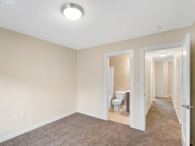 unfurnished bedroom with light colored carpet and connected bathroom