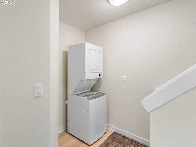 laundry room featuring light hardwood / wood-style flooring and stacked washer and clothes dryer