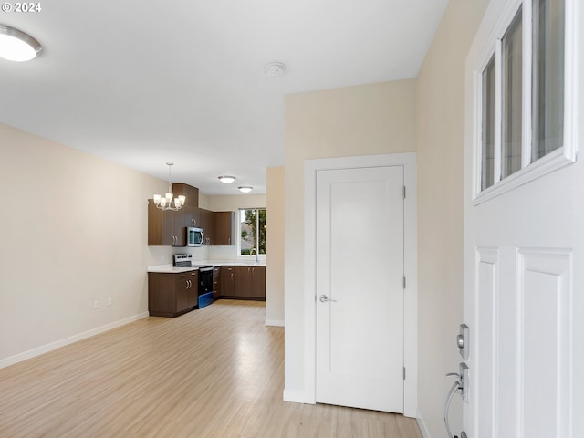 kitchen featuring light wood-type flooring, dark brown cabinets, sink, electric range, and a notable chandelier