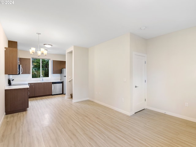 kitchen with sink, an inviting chandelier, stainless steel dishwasher, pendant lighting, and light wood-type flooring