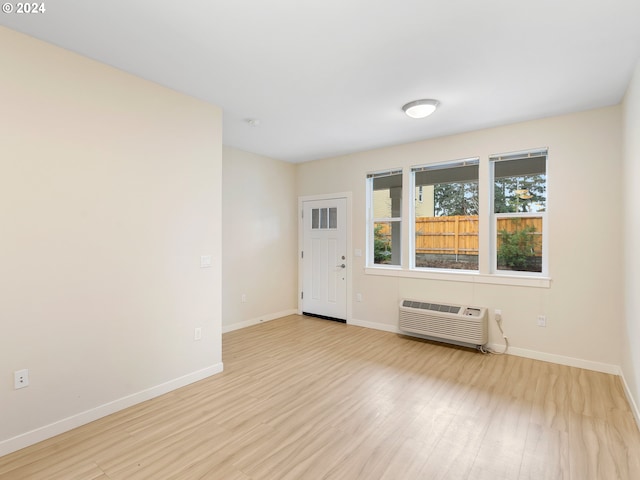 unfurnished room featuring light wood-type flooring and a wall mounted AC