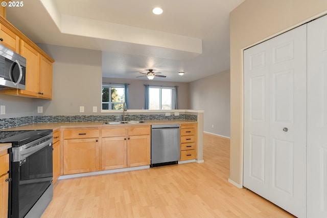 kitchen with ceiling fan, kitchen peninsula, sink, light hardwood / wood-style flooring, and appliances with stainless steel finishes